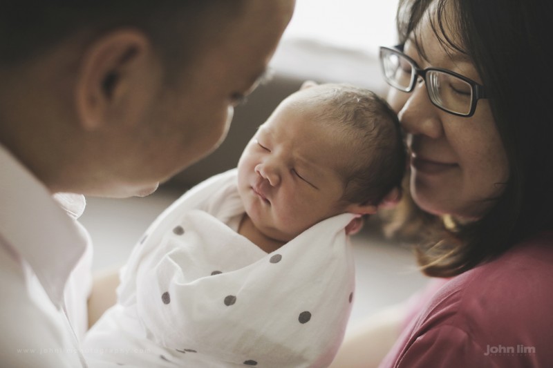 first day in the world of this newborn baby boy, first 24 hours at hospital, held lovingly by father looking on by mother