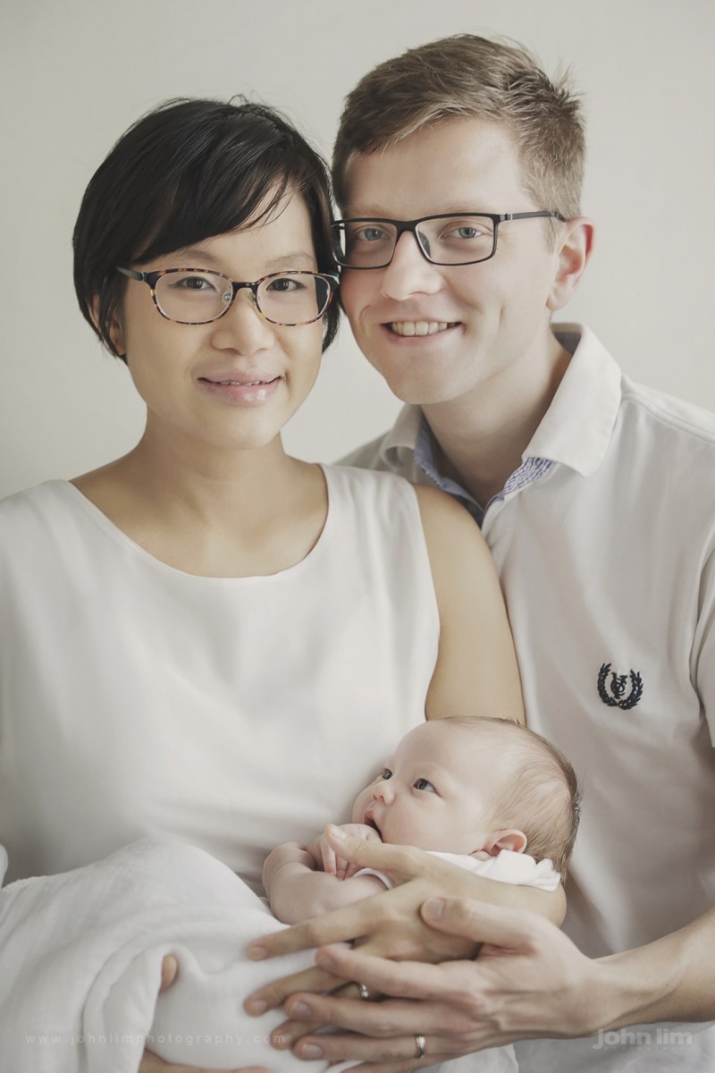 Newborn Studio Photography in Singapore, newborn baby boy family picture with Daddy and Mummy, looking lovingly, baby calm with new parents and with natural window light